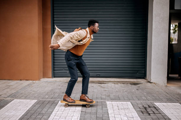 junger gutaussehender geschäftsmann fährt skateboard auf der stadtstraße - city life urban scene skateboarding skateboard stock-fotos und bilder