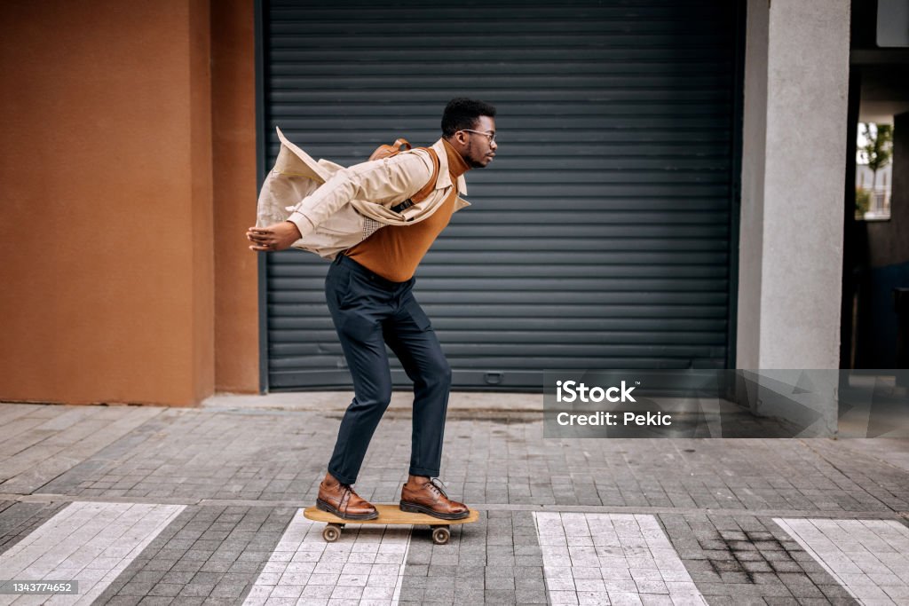 Young handsome businessman driving skateboard on the city street Skateboarding Stock Photo