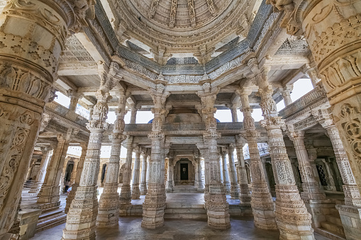 Mount Abu, Rajasthan, India, January 11,2020: Historic Dilwara temple interior architecture with view of intricately carved stone ceiling with columns with beautiful artwork