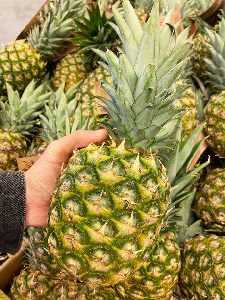 istock Men hand choosing pineapple at supermarket 1343782666