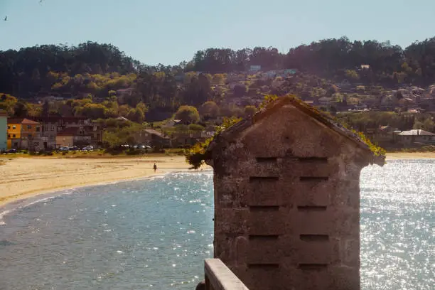 Ría de Aldán, beach and village, hórreo in the foreground, Cangas do Morrazo, Rías Baixas, Pontevedra province, Galicia, Spain.