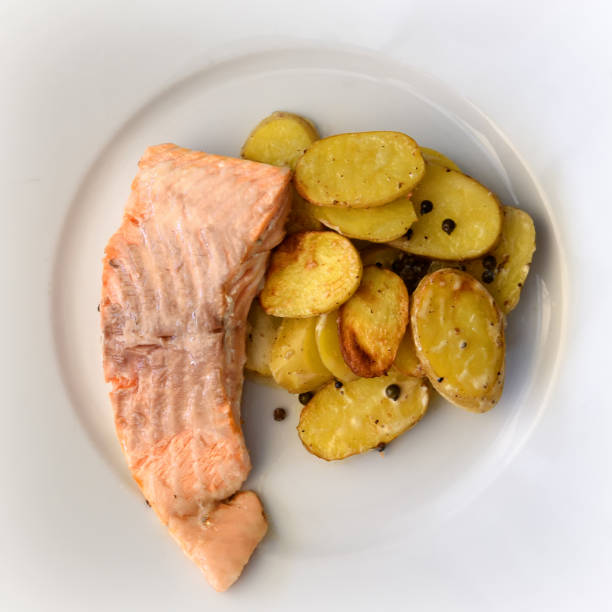 Grilled salmon with baked potatoes on white plate