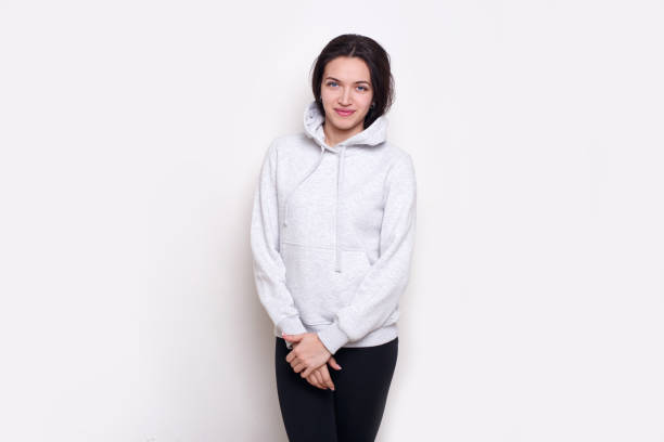 istock Young woman brunette in a light grey sweater, looking at camera, isolated on white background. 1343790936