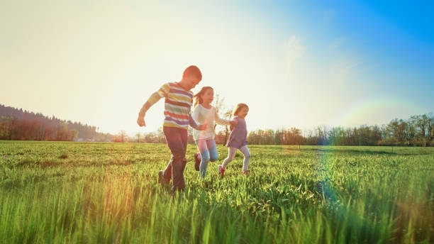 istock Children holding hands while running in a meadow 1343791174