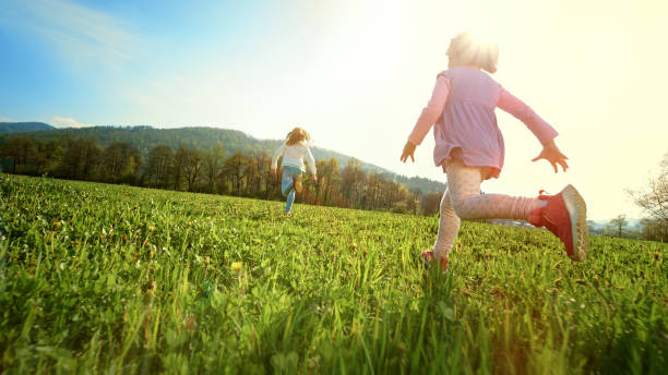girls running in a sunny meadow - child rear view running nature imagens e fotografias de stock