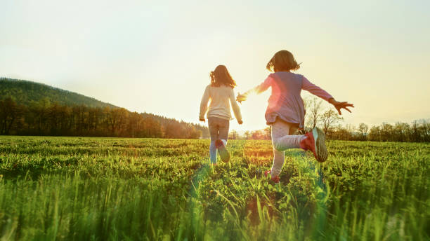 children running in a sunny meadow - child rear view running nature imagens e fotografias de stock