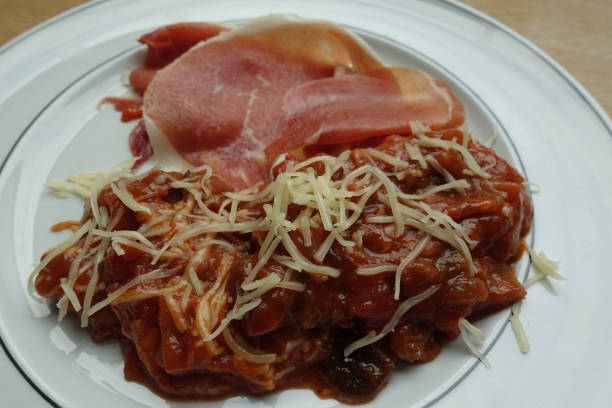 istock Eggplant stew in tomato sauce au gratin served with raw ham 1343795638