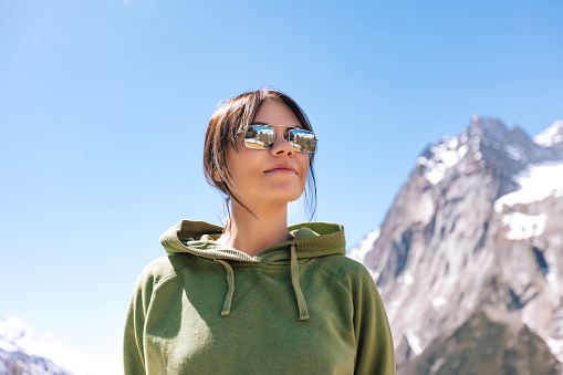 Female portrait of one young woman in sunglasses who is hiking outdoors in mountains. Scenic landscape on the nature. Traveling concept photography