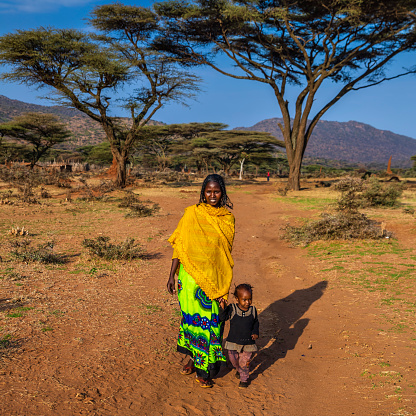 Woman from Borana tribe walking with her baby, southern Ethiopia, Africa. The Borana Oromo are a pastoralist tribe living in southern Ethiopia and northern Kenya.