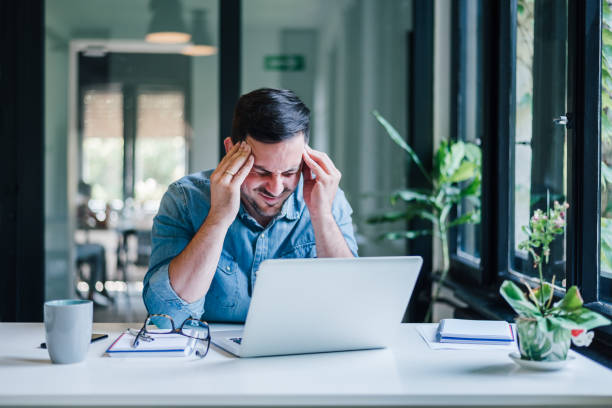 istock Businessman office working holding sore head pain from desk working and sitting all day using laptop computer or notebook suffering headache sick worker overworking concept 1343803225