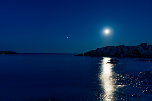 Landscape shot of beach on the Mediterranean sea with full moon reflection