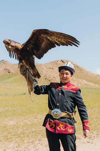 Portrait of a man hunter and his Eagle doing an old tradition of eagle hunting in the wilderness area of Tian Shan mountains, Kyrgyzstan