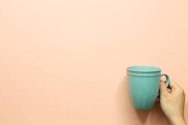 istock Hand holding mint mug cup on pink background. top view, copy space 1343810352