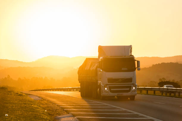 Atibaia, São Paulo, Brazil - May 2, 2021: Truck transporting cargo along the highway at sunset. Various shades of orange and yellow.