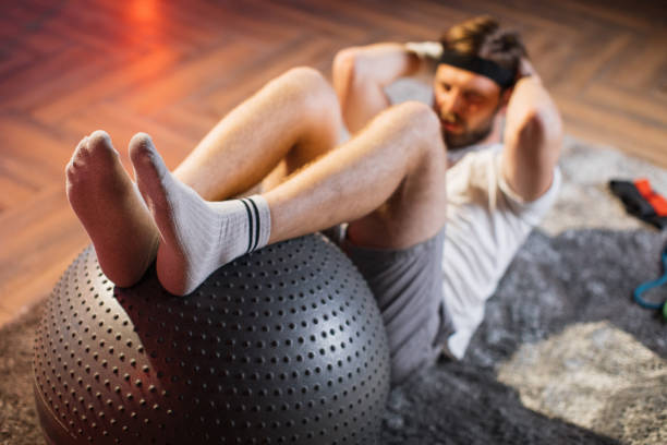 istock Handsome man doing exercises for abs on fitball at home 1343822265