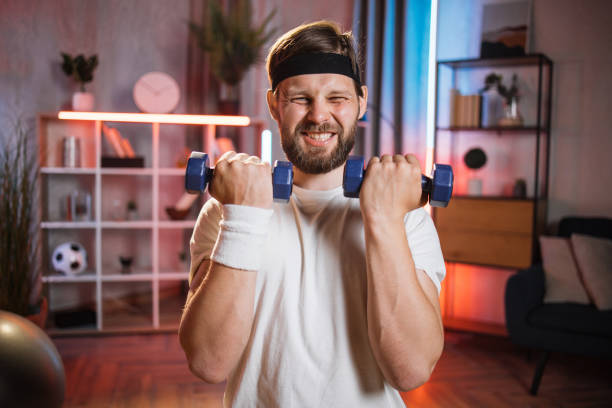 istock Man lifting dumbbells during evening time at home 1343823292