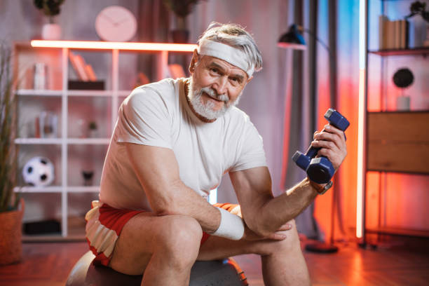 istock Old man sitting on swiss ball and training with dumbbells 1343825597