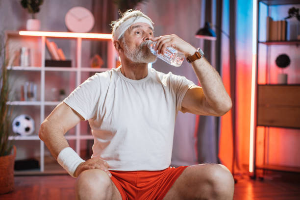 istock Mature man drinking water while sitting on swiss ball 1343825752