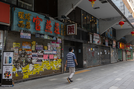 Hong Kong - September 29, 2021 : A man walk past the street in Tsim Sha Tsui, Kowloon, Hong Kong. Many closed-down shops due to the coronavirus outbreak.