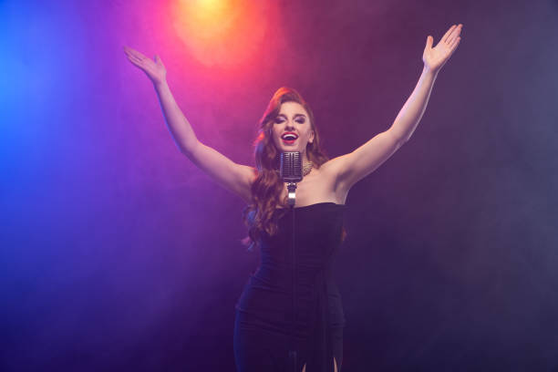 istock Cropped image of beautiful talented stage singer isolated over gradient blue purple background in neon light with stage smoke 1343841768