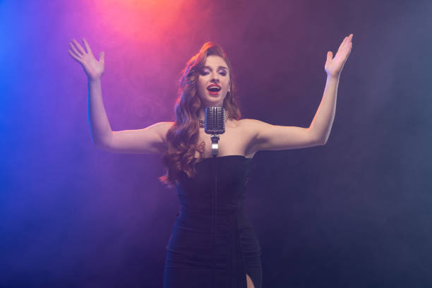 istock Cropped image of beautiful talented stage singer isolated over gradient blue purple background in neon light with stage smoke 1343841774