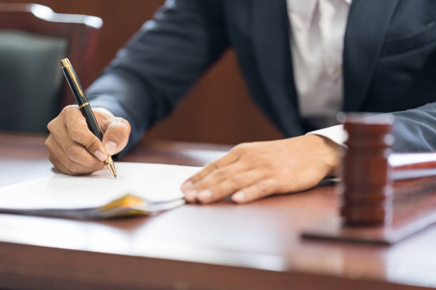 Closeup of judge wooden gavel on sounding block and man handwriting on the background stock photo