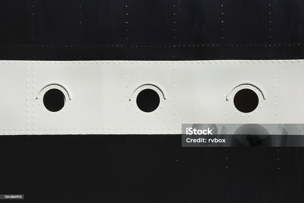 Ship porthole Three porthole window on a ship's hull. Black and white stripes with a round windows on a board the ship with rivets. Black And White Stock Photo