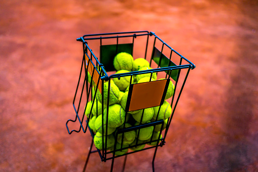 Tennis ball in a basket on clay tennis court