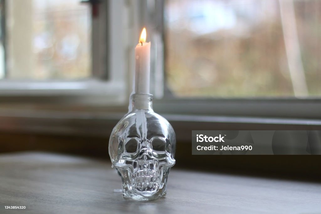 Halloween Decoration Candle in a skull shaped candle holder on a table. Selective focus. Autumn Stock Photo