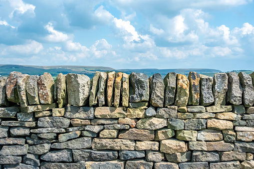 Damaged dry stone wall in the rolling landscape of the southern area of the Yorkshire Dales National Park in England.
