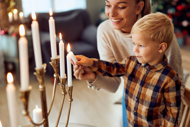 filho e mãe judeus acendendo o menorah para hanukkah em casa. - hanukkah candles - fotografias e filmes do acervo