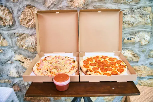 Photo of Two fresh pizzas ham with mushrooms and pepperoni in a box