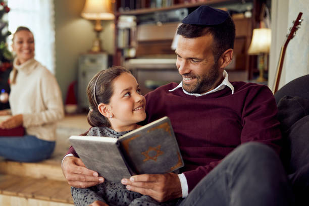 happy father and daughter reading tanakh while relaxing on hanukkah at home. - judaismo imagens e fotografias de stock