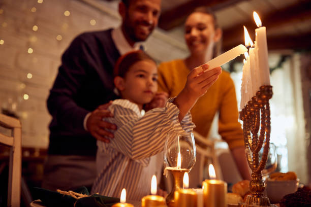 primo piano di una ragazza ebrea che accende candele in menorah durante il pasto in famiglia a hanukkah. - candela attrezzatura per illuminazione foto e immagini stock