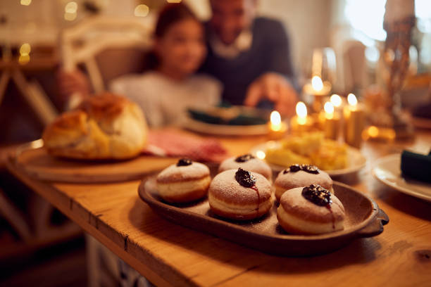 istock Sufganiyah, jam filled donuts on dining table during Hanukkah celebration. 1343862295