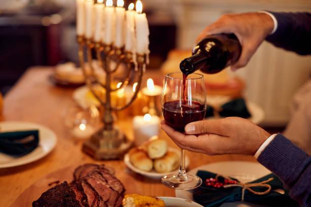 close-up do homem judeu derramando vinho enquanto jantava na mesa de jantar em hanukkah. - kosher wine - fotografias e filmes do acervo