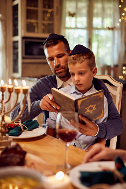padre e hijo judíos leyendo tanaj en la mesa del comedor en janucá. - judaísmo fotos fotografías e imágenes de stock