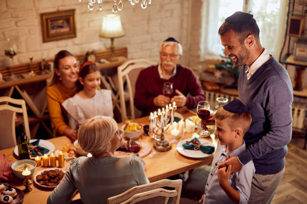 glückliche jüdische großfamilie beim mittagessen am esstisch an chanukka. - judentum stock-fotos und bilder