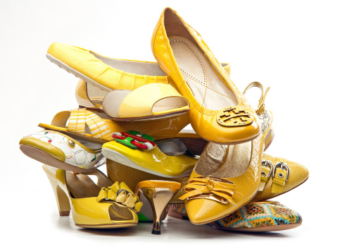 Pile of yellow female shoes isolated on white background