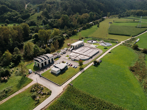 Aerial view of a sewage treatment plant in a green area by a river