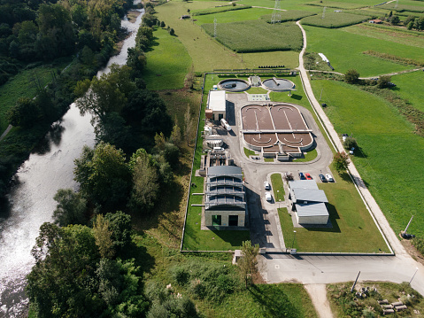 Aerial view of a sewage treatment plant in a green area by a river