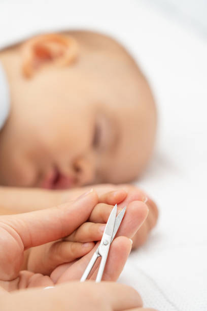 istock Cutting nails of a sleeping baby. Mom cuts her newborn daughter's fingernails while sleeping. Selective focus 1343868268