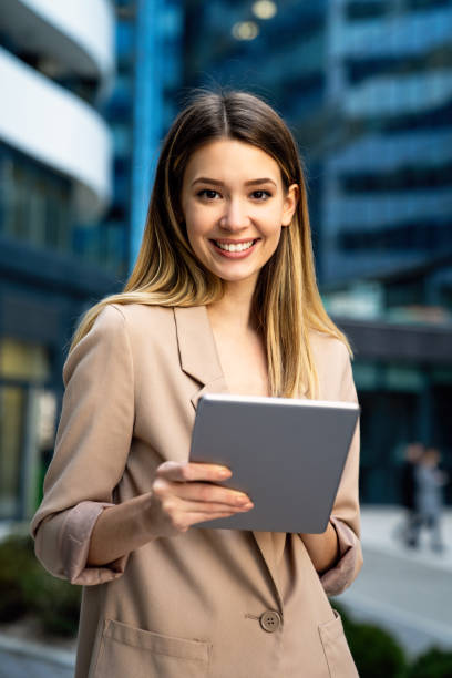 istock Successful businesswoman using a digital tablet while standing in front of business building. 1343868272