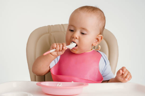 istock The child independently eats cottage cheese with a spoon while sitting on a chair 1343868308
