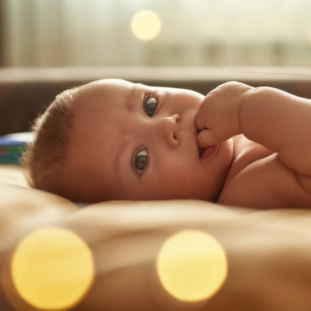 istock Close up baby sucking fingers, looking at camera 1343872650