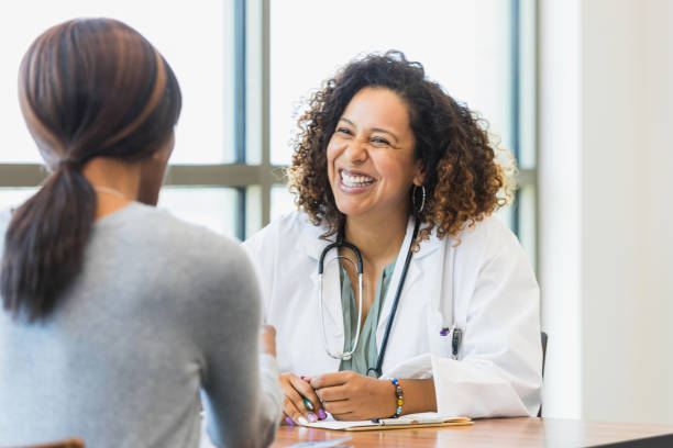 istock Female doctor smiles broadly as unrecognizable patient speaks 1343874701