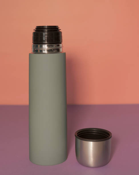 istock Green thermos with open lid on a peach-fiolet background 1343880293
