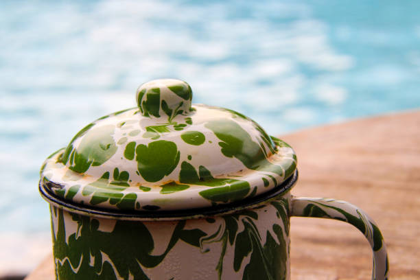 Old-fashioned enamel cup on the table, by the pool.