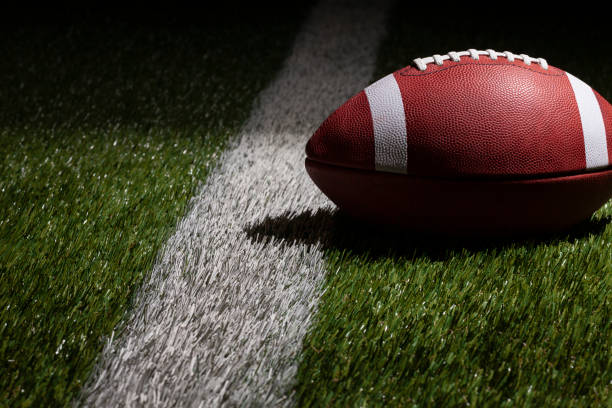 Low angle view of a college style football at a yard line with dramatic lighting stock photo