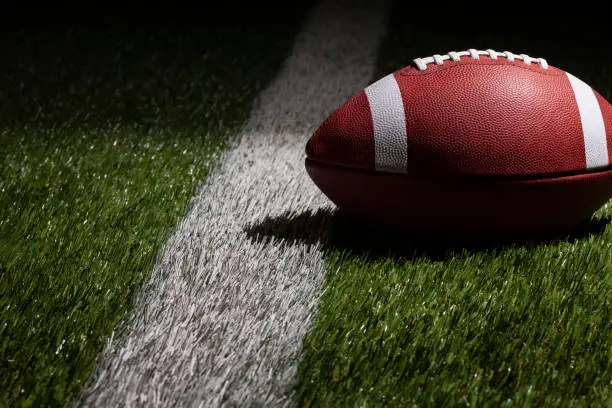 Photo of Low angle view of a college style football at a yard line with dramatic lighting